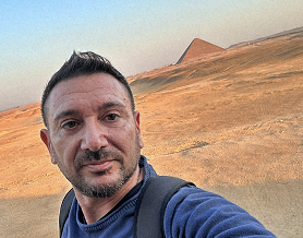 Eros Susca in primo piano nel deserto, con una piramide sullo sfondo, alla scoperta dell’origine della Numerologia