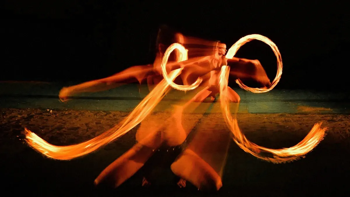 Una persona danza con il fuoco di notte: i cerchi di luce disegnano il sacro fuoco del numero uno