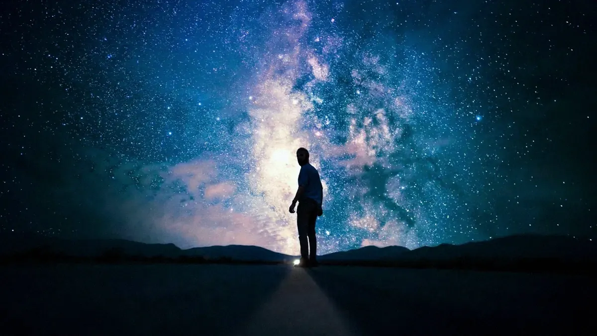 Una persona in piedi su una strada di notte sotto la Via Lattea: l’uomo è il riflesso del cosmo e portatore di armonia sacra